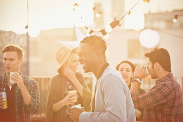 Wall Mural - Young man laughing and drinking at rooftop party