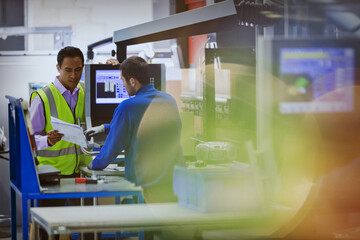 Wall Mural - Supervisor and worker discussing paperwork at machine in steel factory