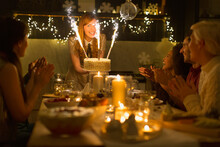 Woman Serving Christmas Cake Sparkler Fireworks To Clapping Family