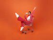 Full lenght portrait of happy smiling Fashionable woman with trolley and showing credit card isolated on orange color background