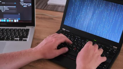Close-up male hands, typing program code on laptops, matrix code on laptop screen. Freelancer and work at home concept.
