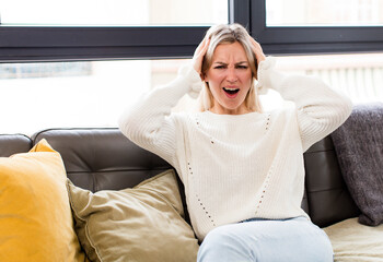 Wall Mural - young pretty woman feeling stressed, worried, anxious or scared, with hands on head, panicking at mistake sitting on a couch