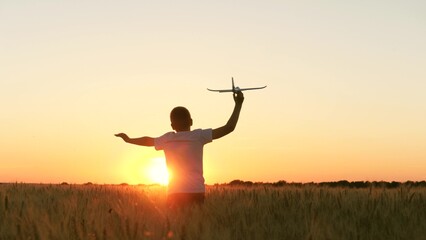 boy teenager child kid runs through field with wheat with toy plane his hands sunset, happy dream family, child wants become pilot pilot astronaut, holding airplane his hands, pilot flight astronaut