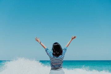 Poster - Young woman rise hand up to sky feel relax and free with summer beach background.