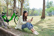 © snowing12 - Women sitting under tree to working and surfing social media on smartphone after cycling in park