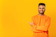 Advertising concept. Cheerful indian guy point finger aside, presenting novelty, paying your attention at empty copy space, brazilian in orange pullover isolated on yellow