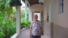 Elderly Woman Standing At Home In Casua South American Residence Backyard. Senior Female Person In 70s, Domestic Authentic Real People
