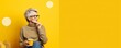 © Road Red Runner - Mature lady drinks tea, isolated on yellow, panoramic studio. AI generated.