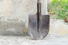 An Old Rusty Shovel.Metal With Wood, An Old Shovel Stands Near The Wall.The Theme Of Agricultural Tools.