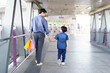 © DG PhotoStock - Happy cheerful Asian little boy and his father walking in the city with carrying a colorful paper shopping bag, father and son walking together in the city or downtown.