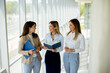 © BGStock72 - Three young business women having a discussion while walking in the office hallway
