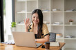 © Wasana - asian young woman has video chat with friends with webcam, Happy young asian business woman waving hands to greeting partner during making video conference with her team.
