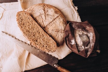 High-angle of freshly baked and sliced bread with flour and a knife on the table