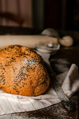 Canvas Print - Vertical close-up of a loaf of wheat bread with poppy seeds on a wooden table