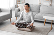 © Pixel-Shot - Young man in pajamas meditating on pillow at home
