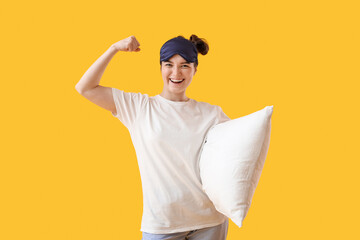 Wall Mural - Happy young woman with sleeping mask and soft pillow on yellow background