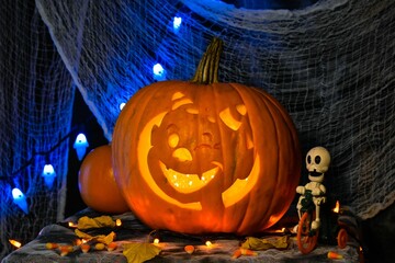 Sticker - Jack-o-lantern, surrounded by sweets for Halloween, with spooky lights and a net in the background