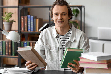 Sticker - Young man with books sitting at table in library