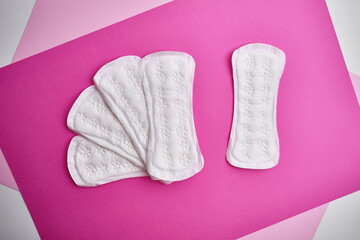 Wall Mural - Women's pads and tampon. Sanitary pads lie next to a tampon on an isolated background on a pink and white background. The concept of health, feminine hygiene and the menstrual cycle