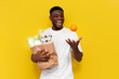© Богдан Маліцький - happy african american male shopper holding eco bag with groceries and nodding orange