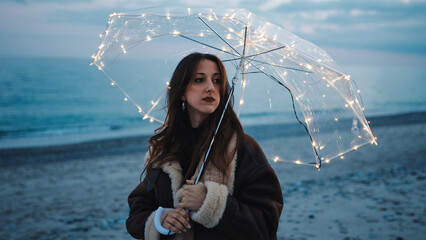 Wall Mural - Glowing umbrella of a girl walking on the beach in the night outdoor
