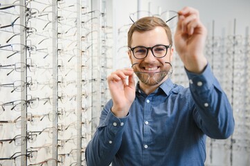 Wall Mural - Man evaluating quality of glasses in optical shop