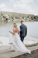 Wall Mural - Vertical shot of a beautiful bride and groom standing together on a lake shore