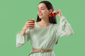 Canvas Print - Young woman with glass of vegetable juice and tomatoes on green background