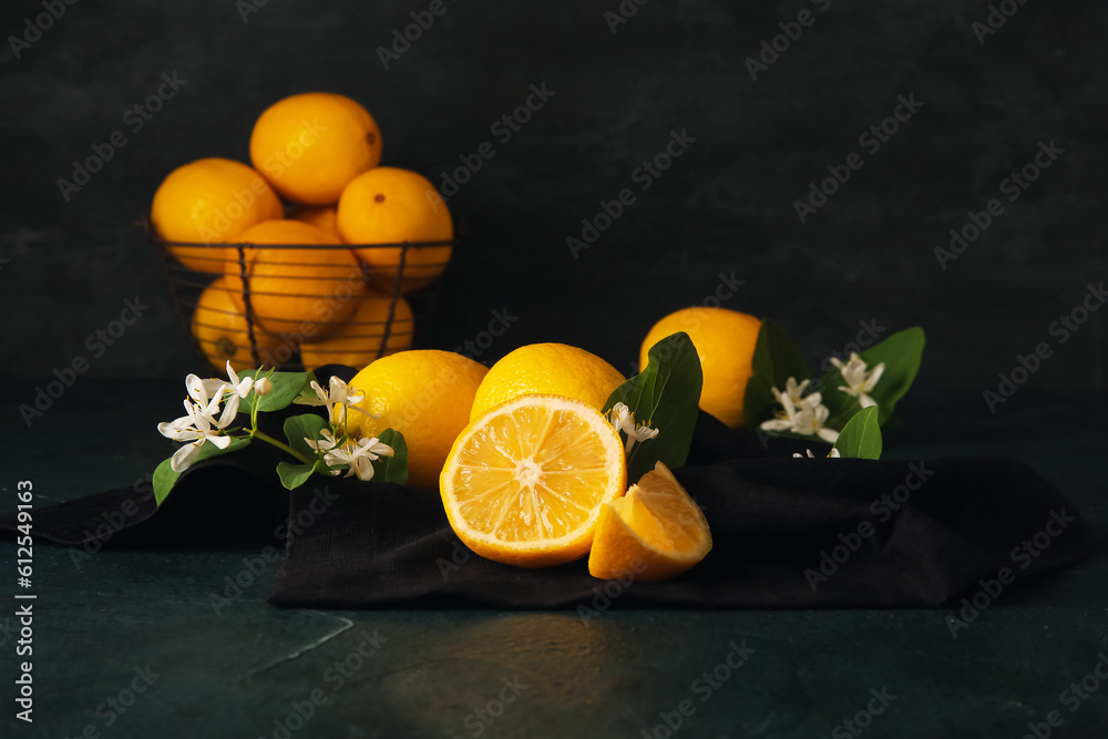 Board and basket of lemons with blooming branches on black background