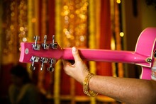 Close-up Shot Of A Hand Holding A Pink Guitar With A Blurred Background