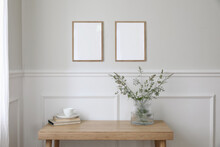 Two Empty Vertical Picture Frame Mockups Hanging On Wall. Cup Of Coffee, Books. Wooden Desk, Table. Vase, Green Grasses And Cow Parsley. Minimal Working Space, Home Office. Elegant Scandi Interior.
