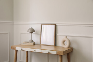 Wall Mural - Modern living room, home office. Trendy round vase, beige lamp and old books. Blank picture frame mockup. Bamboo table with white drawers. Minimal Scandi boho interior, home. Beige wall background.