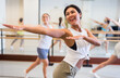 © JackF - Positive asian woman engaged in dancing in a female group practices energetic swing in a dance studio