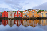 Fototapeta Tęcza - A row of typical colourful Norwegian houses built on pillars on top of a water surface. Reflecting on the water surface.