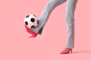 Legs of young woman wearing high heels and playing with soccer ball on pink background