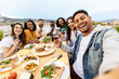 © Xavier Lorenzo - Happy group of people toasting red wine at eatery barbecue lunch party. Multiracial friends taking selfie portrait together enjoying food and drink at summer celebration. Friendship concept