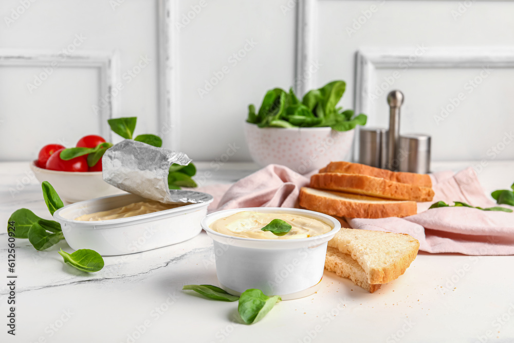Boxes of processed cheese, toasts and vegetables on white grunge table near wall