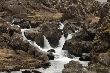 Sticker - a mountain stream in the middle of some rocks and grass