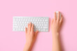Female hands with modern computer keyboard and mouse on pink background