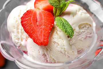 Bowl of vanilla ice cream with strawberries and mint on table, closeup