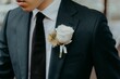 © Bec L/Wirestock Creators - Closeup of a beautiful rose pinned to the suit of a young groom