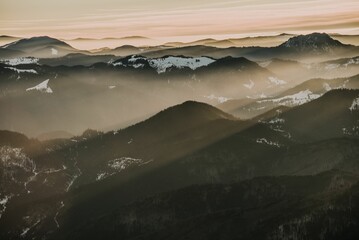 Wall Mural - Aerial view of the mesmerizing dreamy sunrise over snowy forested mountains - great for a wallpaper