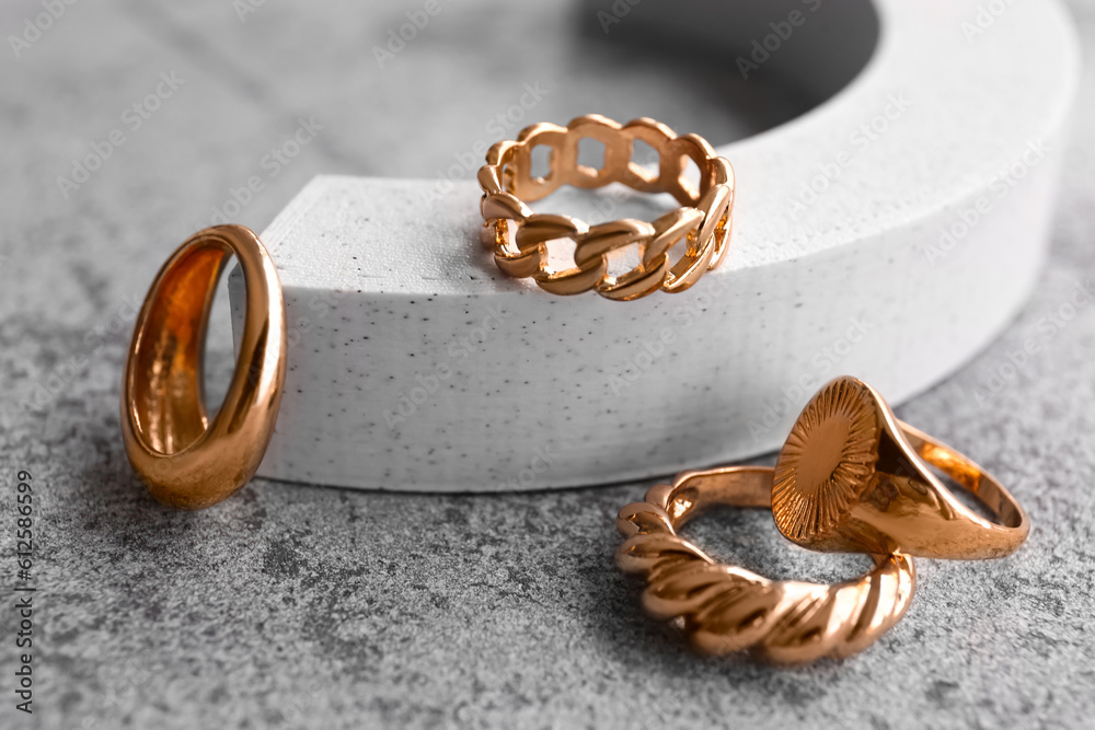 Decorative podium with different golden rings on grunge grey background