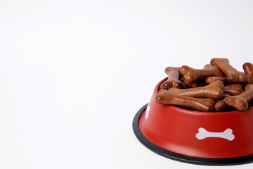 Wall Mural - Red bowl with bone shaped dog cookies on white background, space for text