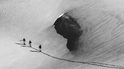 Wall Mural - Grayscale beautiful view of skiers on a snowy mountain during sunrise