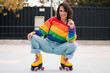 © Nano - bella mujer latina sonriendo, con frenillos, maquillaje y en patines con polera de arcoíris lgbtq en la calle practicando patinaje