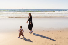 Mom Walking With Baby On The Beach
