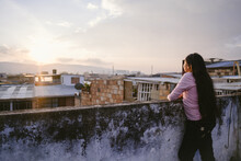Woman Leaning On Rooftop Wall Admiring The View
