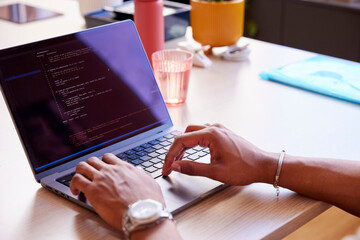 Anonymous coder typing on laptop at table