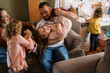 © Serena Burroughs/Stocksy - Smiling happy family playing with kids on couch in home
